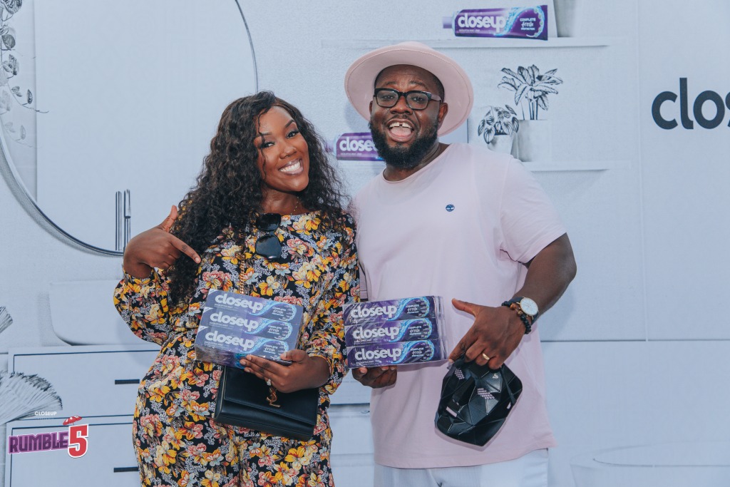 Two guests holding CloseUp packs in front of a branded wall