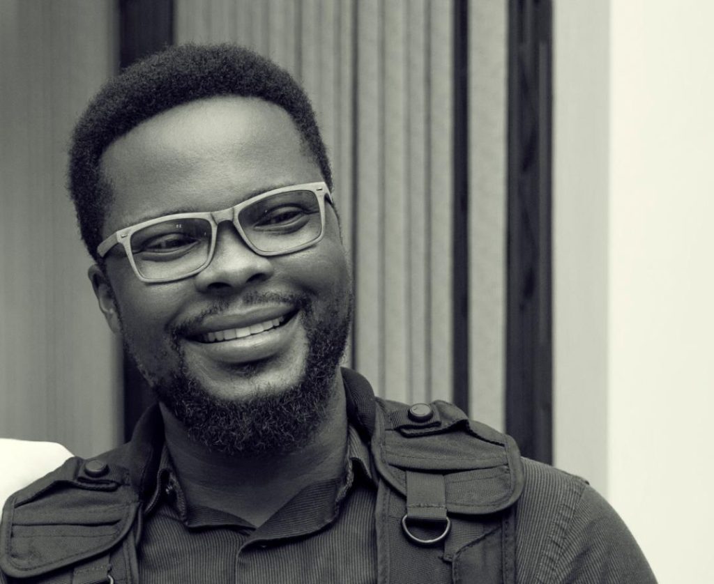 Black and white portrait of a man with glasses, smiling