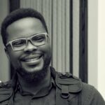 Black and white portrait of a man with glasses, smiling