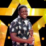 A creator smiling in front of a large gold star backdrop