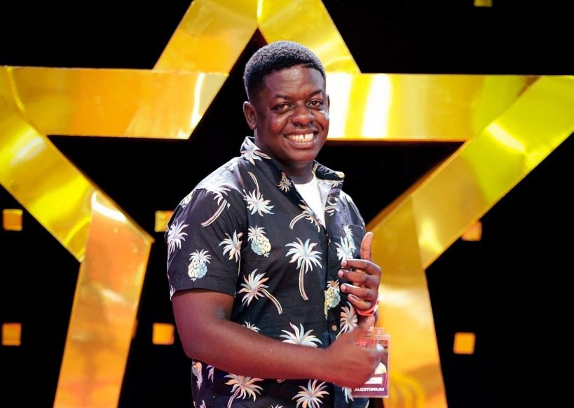 A creator smiling in front of a large gold star backdrop