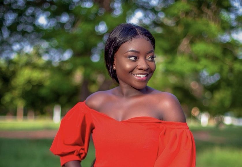 Portrait of a woman in a red off-shoulder top photographed outdoors