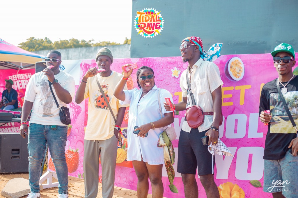 Festival-goers posing in front of a pink Tidal Rave photo wall