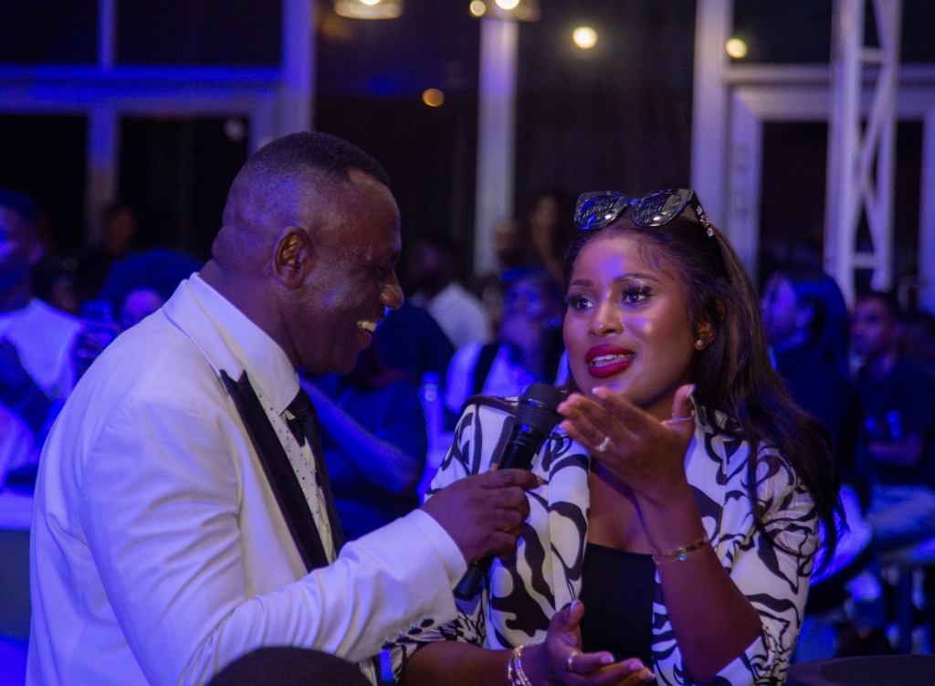 A host holding a microphone talking with a guest at the launch event