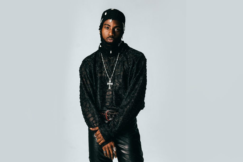 Studio portrait of a musician dressed in black against a pale grey backdrop