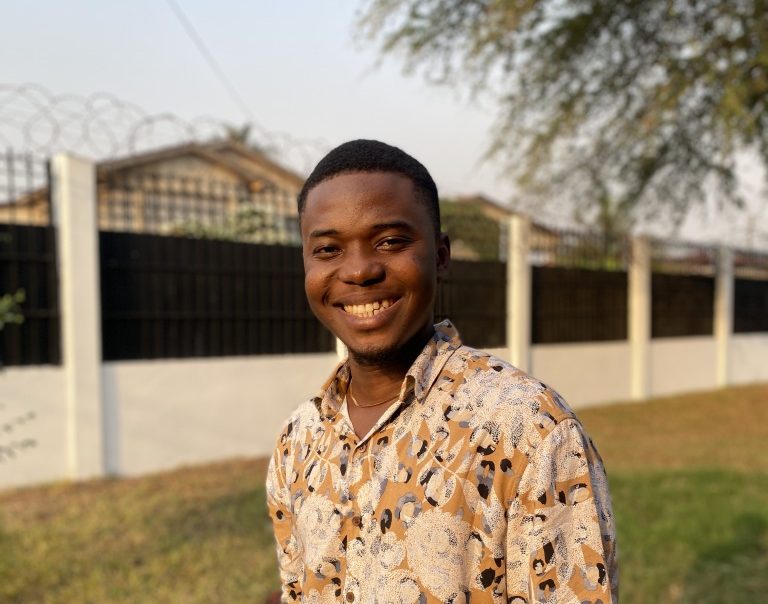 Portrait of a young man smiling outdoors in a patterned shirt