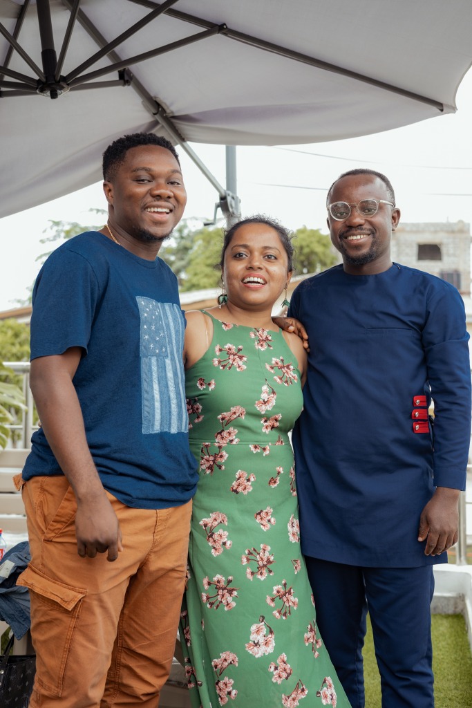 Three colleagues standing arm in arm under a parasol