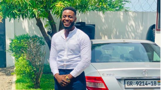 A man in a white shirt standing beside a parked car