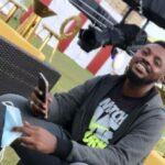 A creator seated outdoors holding up a phone to film