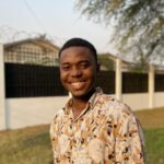Portrait of a young man smiling outdoors in a patterned shirt