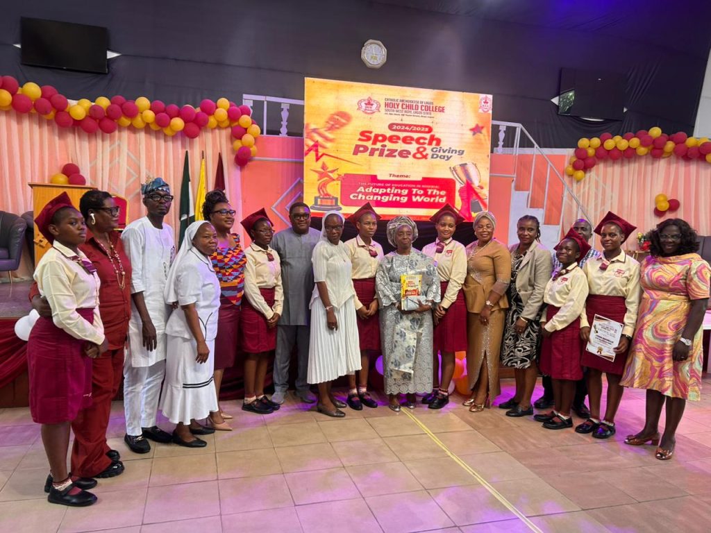 Students in school uniform standing on stage with guests at a speech and prize-giving day
