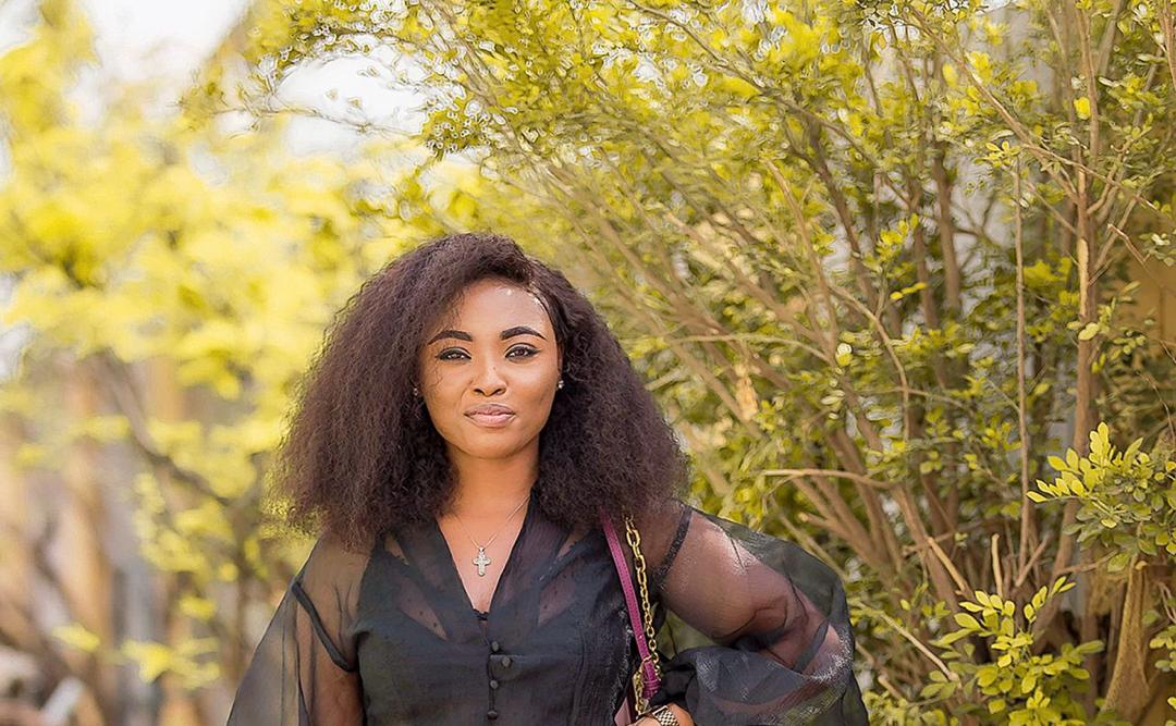 Portrait of a woman in a black top standing among foliage